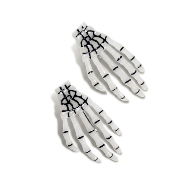 Glow-in-the-dark skeleton hand hair clip pair, shown glowing