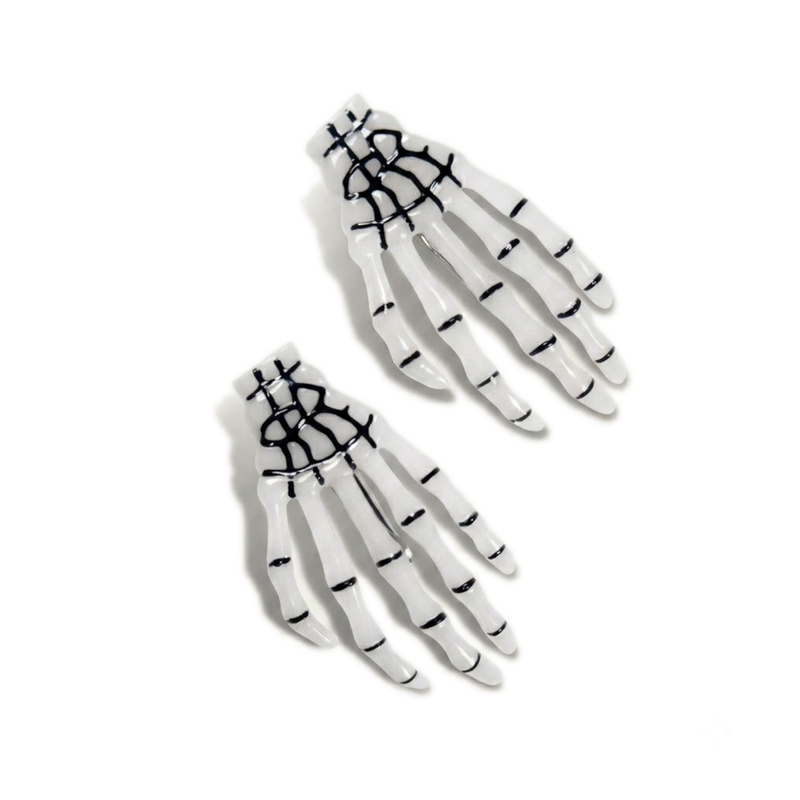 Glow-in-the-dark skeleton hand hair clip pair, shown glowing