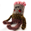 Hand-crocheted zombie plush with grey skin and brown pants